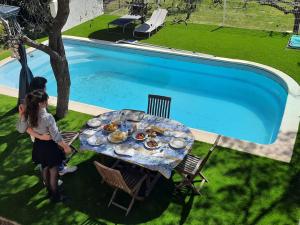 Eine Frau steht neben einem Tisch mit Essen neben einem Pool in der Unterkunft Villa climatisée piscine in Montpellier