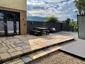 um pátio com uma mesa de madeira e um banco em Stylish, central studio with kitchen & large deck em Fort William