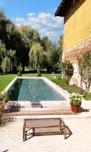 ein Pool mit einer Bank neben einem Gebäude in der Unterkunft Villa de 5 chambres avec piscine privee jacuzzi et jardin amenage a Saint Paul de Varax in Saint-Paul-de-Varax
