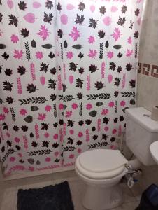 a bathroom with a toilet and a shower curtain with flowers at Departamentos el Peregrino in San Luis