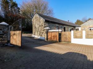 an old stone building with a wooden gate and fence at The Stables in Camelford