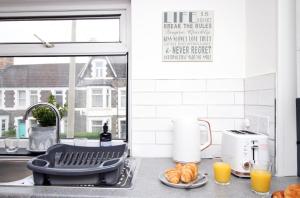 een aanrecht met een wastafel met brood en jus d'orange bij One Bedroom Apartment | Smart TV and WiFi in Cardiff