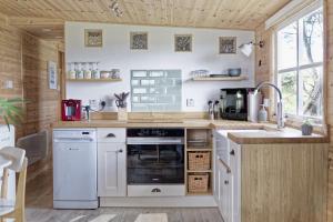 a kitchen with white appliances and a wooden ceiling at Scandi Cabin On A Hill, With Stunning Views Across Cornwall in Nancledra