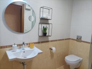 a bathroom with a sink and a mirror and a toilet at HyP - Ático Forneira in Arcade