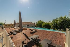a deck with chairs and umbrellas next to a pool at Séquoia furnished apartment in Antibes