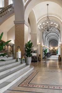una grande hall con scale e lampadario a braccio di Grand Hotel di Parma a Parma
