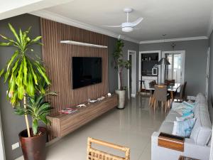 - un salon avec un canapé et une télévision dans l'établissement Guaruja Praia de Pitangueiras frente ao mar, à Guarujá