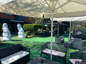 un patio con mesas y sillas bajo una sombrilla blanca en Hotel Motel Visconteo en Binasco