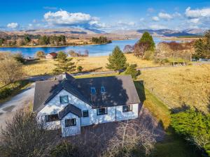 an aerial view of a house in a field next to a lake at Brackenbrae Holiday Cottage in Acharacle