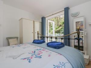 a bedroom with a bed with blue sheets and a window at Longships in Penzance