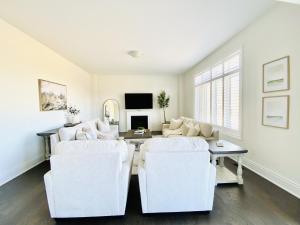 sala de estar con 2 sillas blancas y mesa en Snow Valley Hideaway, en Barrie