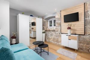 a living room with a blue couch and a stone wall at Apartman Barocco Lovran in Lovran