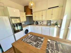 a kitchen with white cabinets and a table with a picture on it at Maison Confort & Silence, Jardin & Barbecue in Marseille