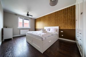 een slaapkamer met een wit bed en een houten vloer bij Wrocław Partynice Cosy Apartment in Wrocław