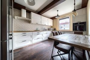 cocina con armarios blancos y mesa de madera en Wrocław Partynice Cosy Apartment en Wroclaw