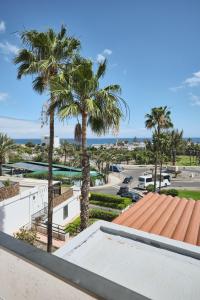 a view of a parking lot with palm trees at Lovely Apartment in San Agustín: Steps Away from Playa Del Inglés and Maspalomas! in San Bartolomé de Tirajana