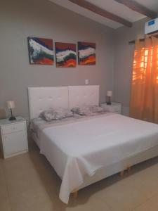 1 dormitorio con 1 cama blanca y 3 pinturas en la pared en Quality time en Luján de Cuyo
