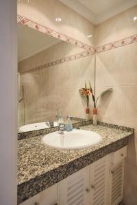a bathroom with a sink and a mirror at Lovely Apartment in San Agustín: Steps Away from Playa Del Inglés and Maspalomas! in San Bartolomé de Tirajana