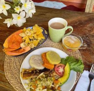 a table with a plate of food and a cup of coffee at Real Jamaica - Cabin right beside the sea-Papa Curvins Yard in Oracabessa