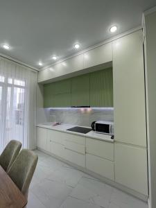 a kitchen with white counters and green cabinets at Нурсултан-сити in Astana