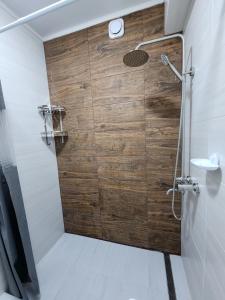 ein Bad mit einer Dusche und einer Holzwand in der Unterkunft Diamond Apartment in Osch