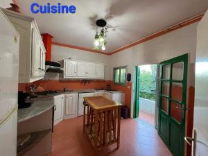 eine Küche mit weißen Schränken und einer grünen Tür in der Unterkunft Villa Bel air in Ain Draham