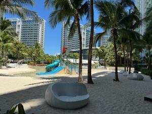 einen Spielplatz mit einer Bank im Sand mit Palmen in der Unterkunft Azure Urban Resort - By Ground Zero One in Manila