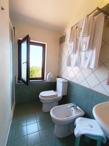 bagno con servizi igienici, lavandino e finestra di Villa Hirschen a Zafferana Etnea