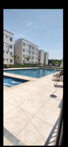 a swimming pool with two chairs and some buildings at Apartamento Incrivel in Campo Grande