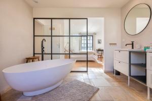 une salle de bain avec une grande baignoire blanche et une chambre dans l'établissement Chalet Soleil Blanc au pied des pistes, à Saint-Gervais-les-Bains