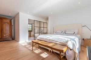 - une chambre blanche avec un grand lit et un banc en bois dans l'établissement Chalet Soleil Blanc au pied des pistes, à Saint-Gervais-les-Bains