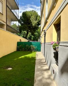 een groene tuin naast een gebouw met een hek bij MONO Apartments Aldini in Bologna