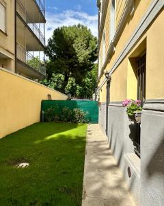 a green yard next to a building with a fence at MONO Apartments Aldini in Bologna