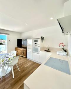 eine Küche mit weißen Schränken und einem Tisch und Stühlen in der Unterkunft Holiday Valley Fortuna in Adeje