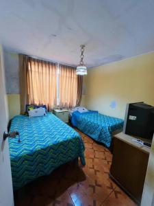 a bedroom with two beds and a tv in it at Bungalow acogedor cerca a todo in San Bartolo