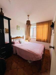 a bedroom with a bed with pink sheets and a window at Bungalow acogedor cerca a todo in San Bartolo