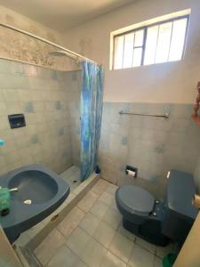 a bathroom with a blue toilet and a tub at Bungalow acogedor cerca a todo in San Bartolo