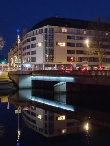 un pont sur une masse d'eau la nuit dans l'établissement City'O apparthotel, à Caen