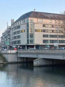 un pont sur une rivière à côté d'un bâtiment dans l'établissement City'O apparthotel, à Caen