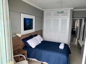 1 dormitorio con 1 cama con sábanas azules y almohadas blancas en Guaruja Praia de Pitangueiras frente ao mar, en Guarujá