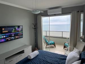 a bedroom with a bed and a flat screen tv at Guaruja Praia de Pitangueiras frente ao mar in Guarujá