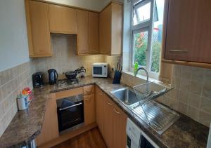 a kitchen with wooden cabinets and a sink at Coventry 59 Michaelmas Pet Friendly 2 Bedroom Apt with Parking in Parkside