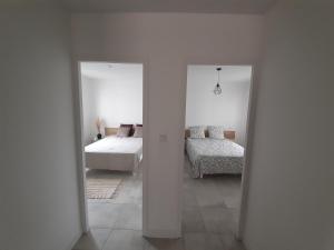 Résidence Camus في بلوا: غرفة نوم بيضاء بسريرين ومرآة