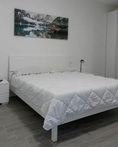 a white bed in a bedroom with a painting on the wall at Appartamento La Corte in Levico Terme