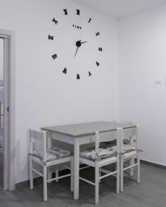 a table with chairs and a clock on a wall at Appartamento La Corte in Levico Terme