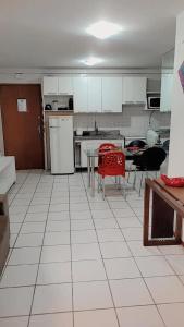 een keuken met witte kasten en een tafel met rode stoelen bij Apartamento Catamarã Port Ville Pajuçara Maceió in Maceió