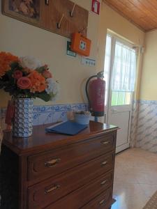 a dresser with a vase of flowers on top of it at Casas do Castelo in Aldeia da Serra