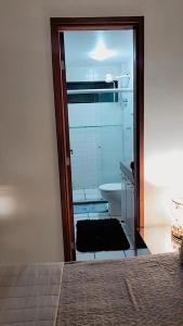 een slaapkamer met een deur naar een badkamer met een spiegel bij Apartamento Catamarã Port Ville Pajuçara Maceió in Maceió