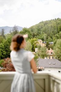 Eine Frau in einem weißen Kleid steht auf einem Balkon in der Unterkunft Boutiquehotel Hubertushof in Bad Ischl