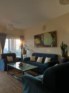 una sala de estar con sofás azules y una mesa. en Sunset Villa, en Coonoor